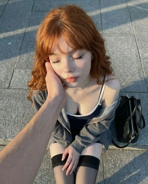Fictional adult red-haired woman in a relaxed indoor setting